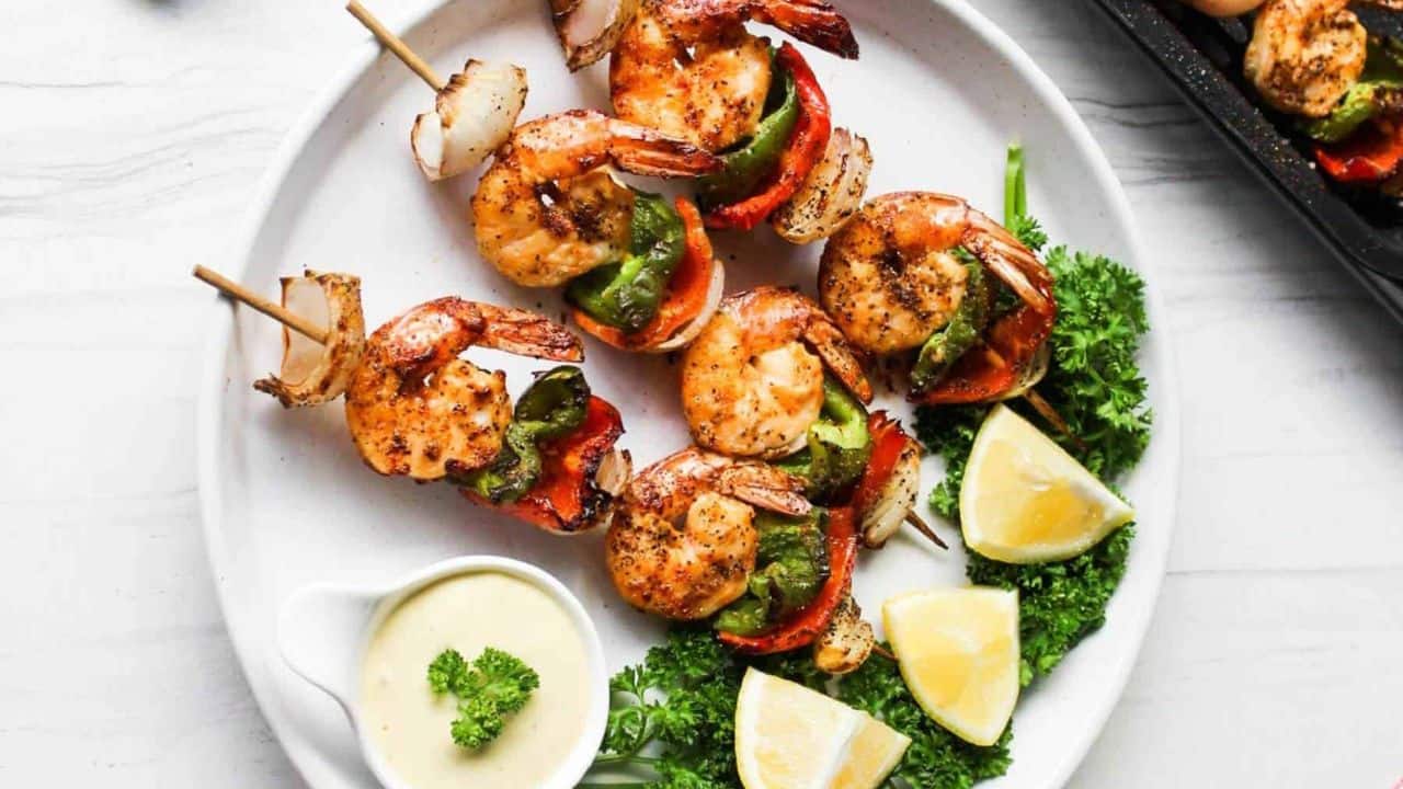 Shrimp skewers on a plate with lemon wedges.