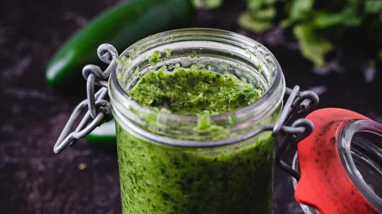 Green hot sauce on black background.