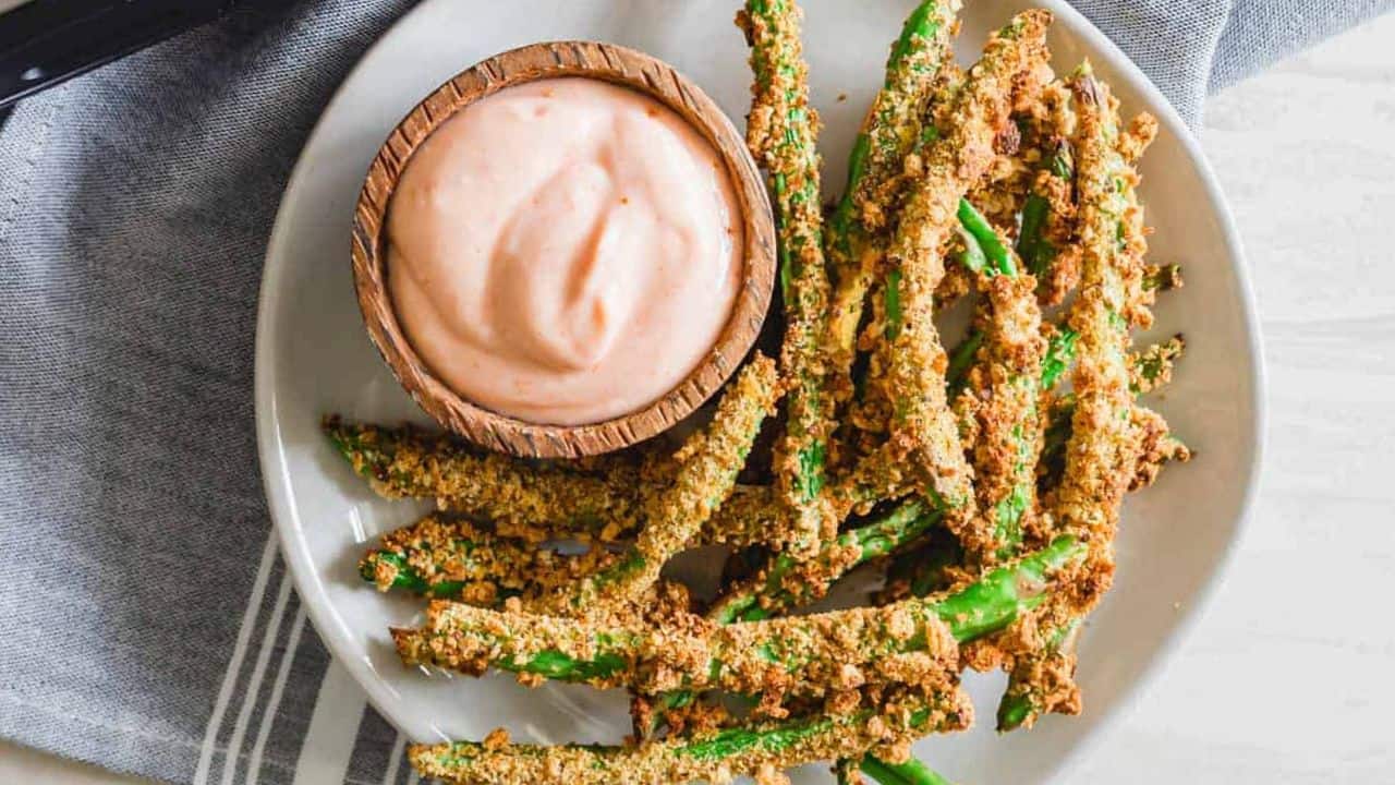 Crispy air fryer green bean fries with yogurt dip on a plate.