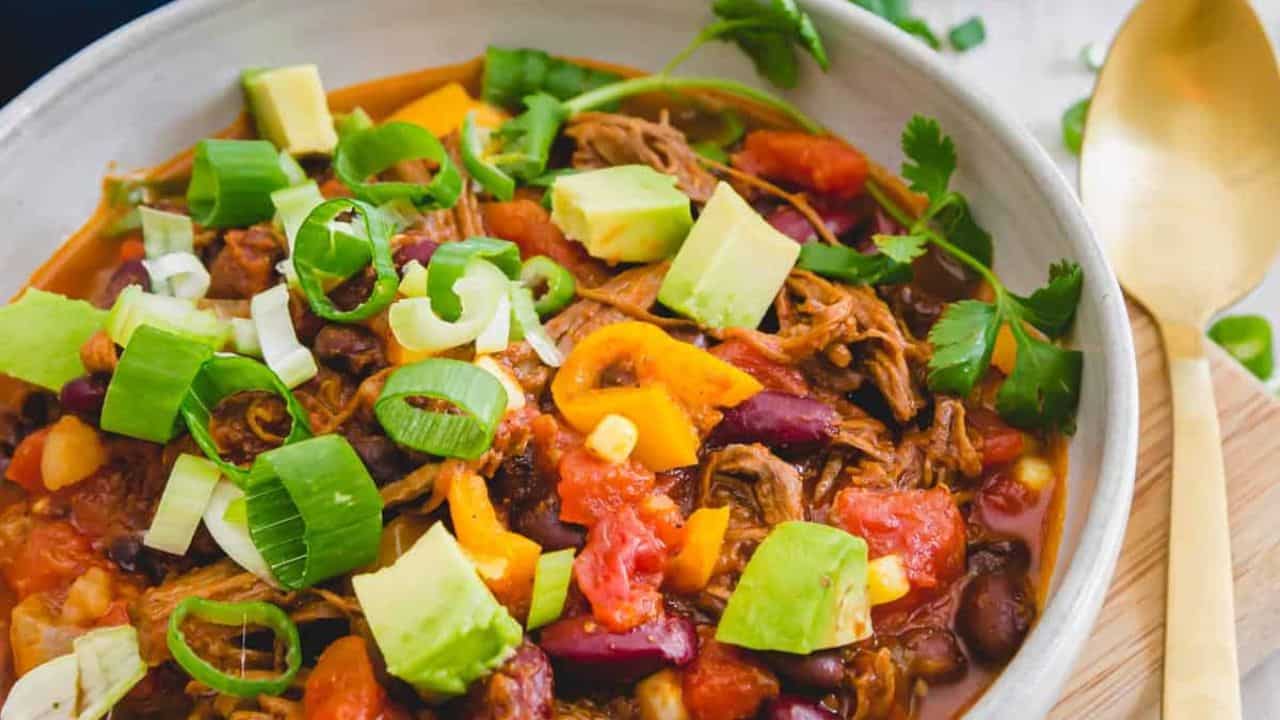 Brisket chili in a bowl topede with green onions and avocado.