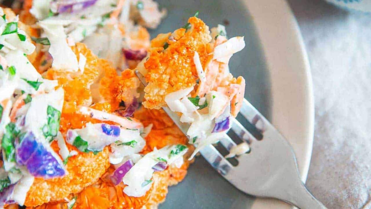 Buffalo cauliflower streaks with blue cheese coleslaw on a plate.