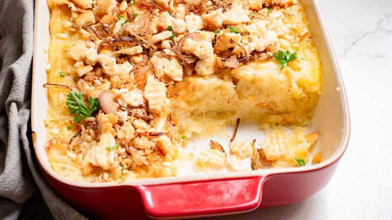 Masshed potato casserole in a baking dish with a cracker crumb topping.