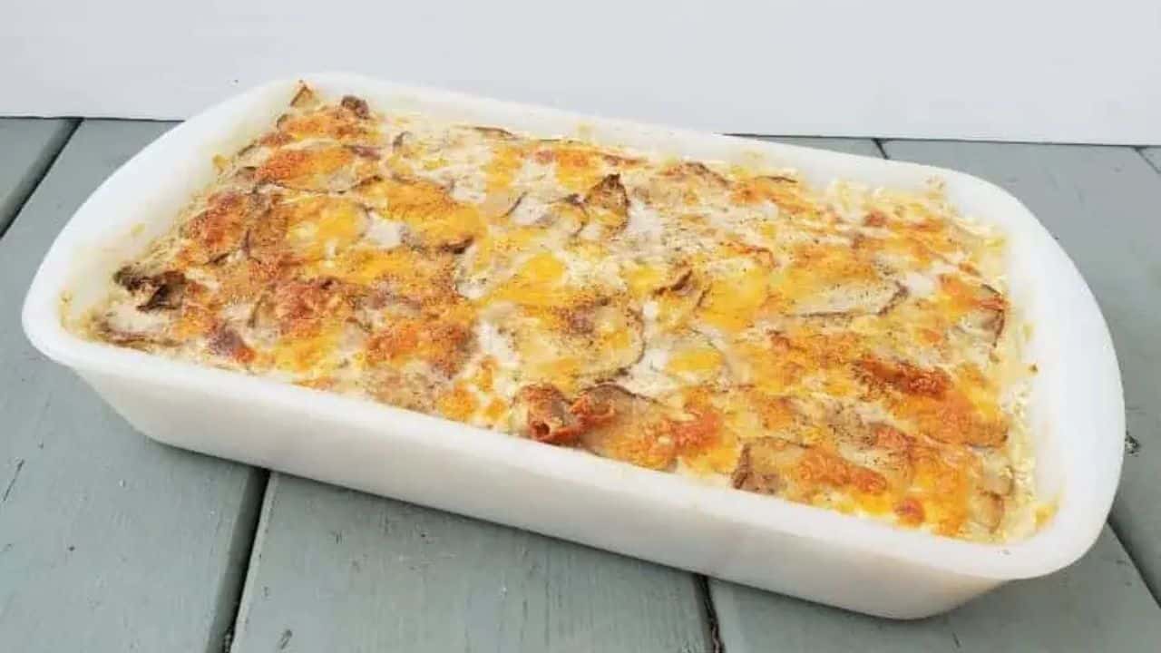 Cheesy scalloped potatoes in a casserole dish on a blue wooden table.