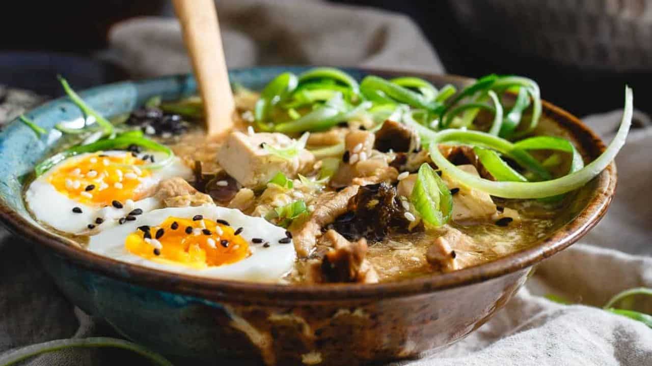 A bowl of soup with an egg on top.