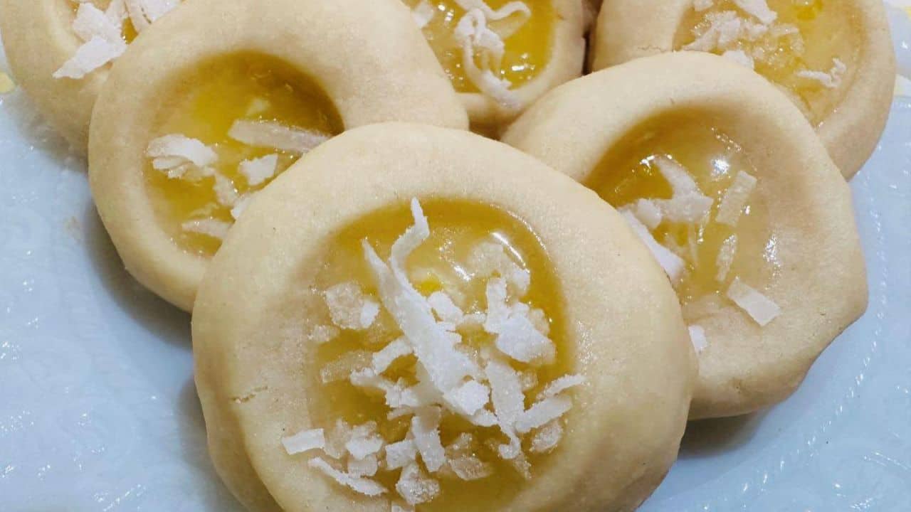 Lemon cookies on a plate with a yellow checkered tablecloth.