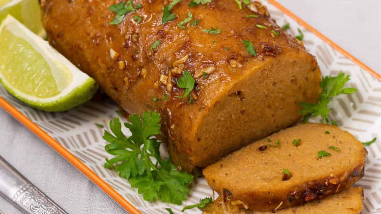 Vegan Turkey Roast in a glass baking dish on a countertop, garnished with herbs.