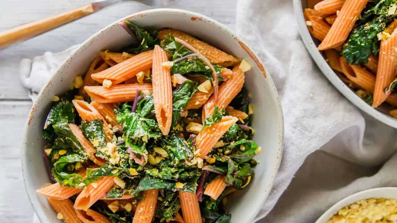 Red lentil pasta with garlic lemon greens in a bowl.