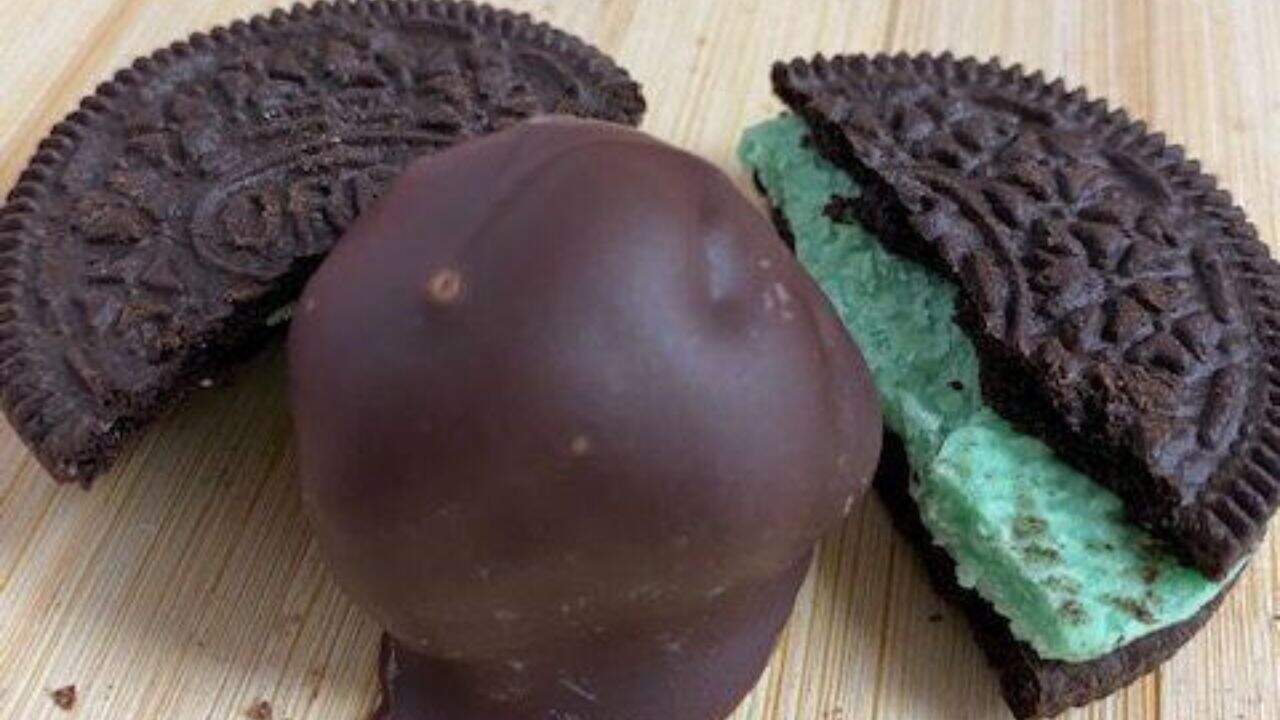 A mint truffle in the middle of a broken mint Oreo cookie with green icing.