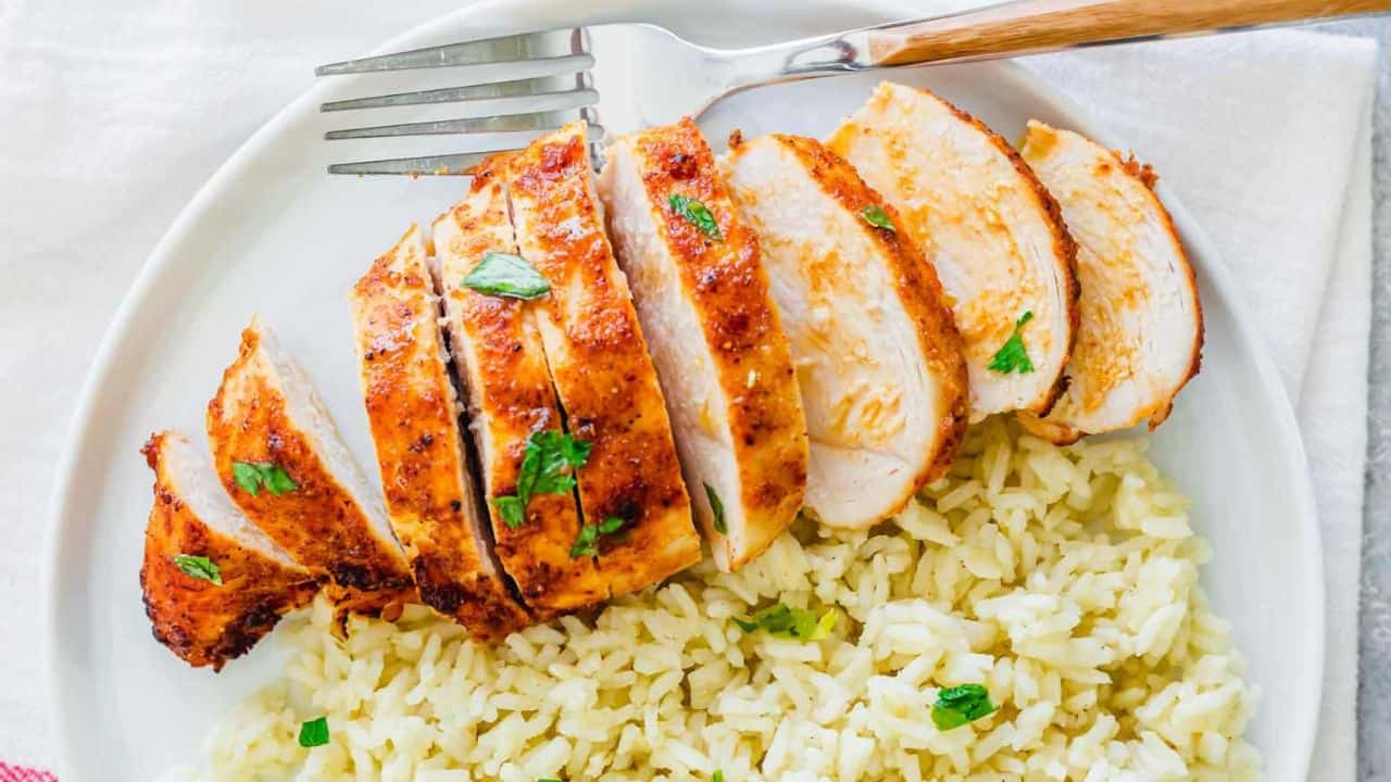 Air fryer frozen chicken breast sliced on a plate with rice and a fork.