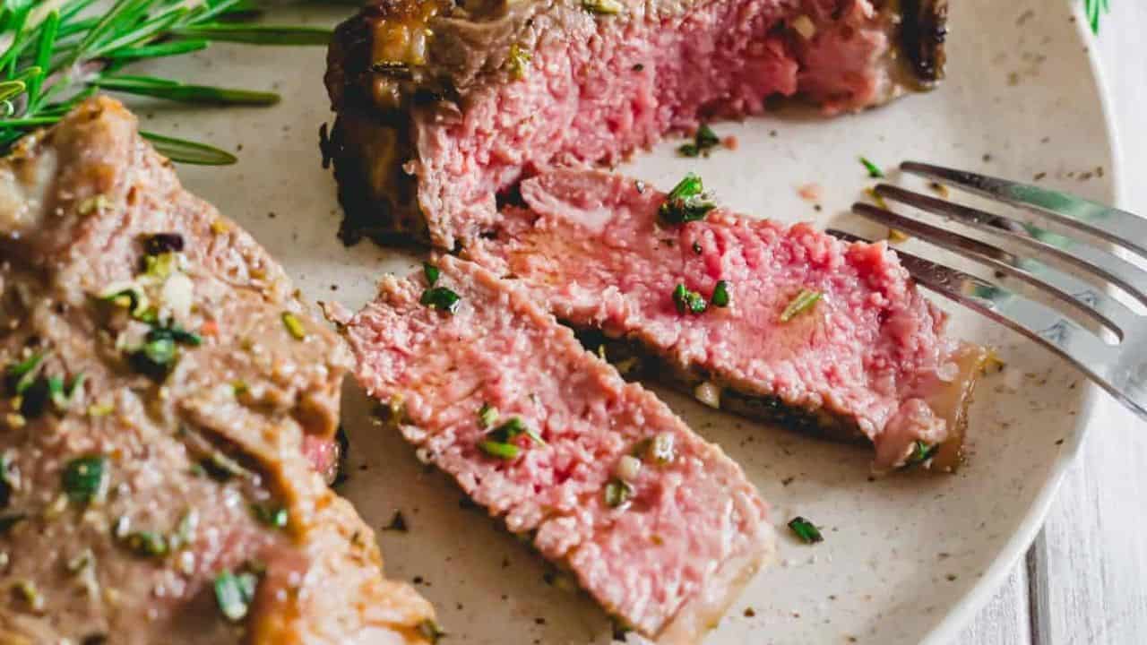 Air fryer lamb chops sliced on a plate with fresh rosemary sprigs.