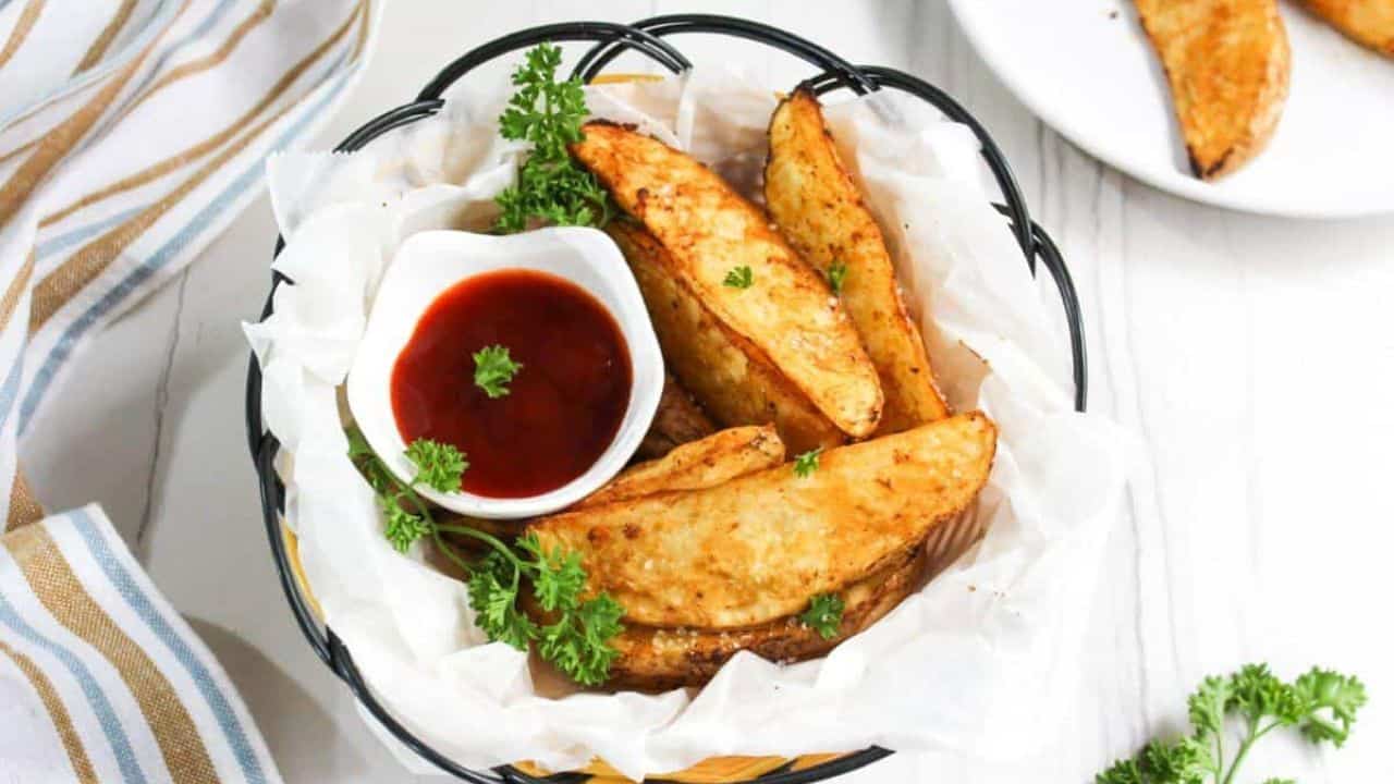 Fried potato wedges with ketchup and parsley.