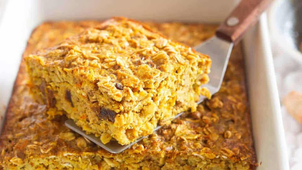 Turmeric baked oatmeal slice on a white plate with fresh blueberries.