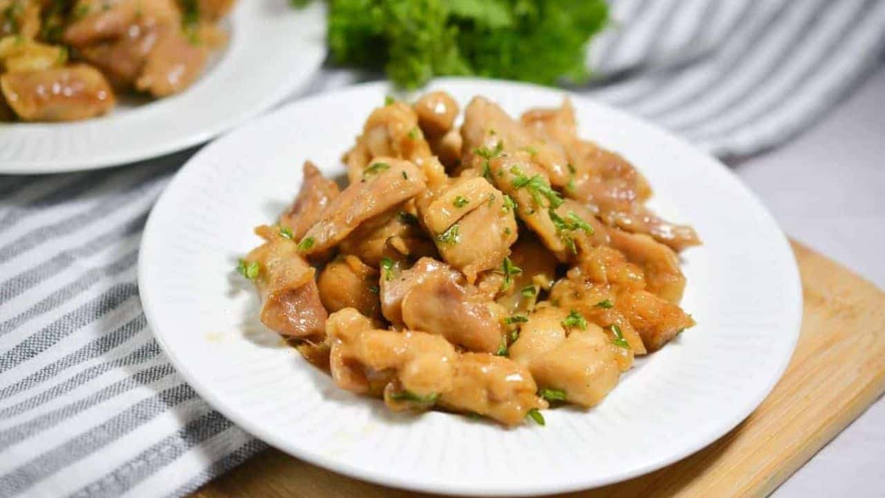 A white plate with chicken and parsley on it.