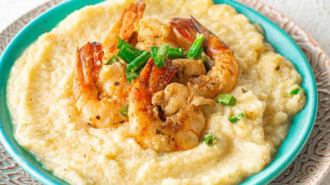 A bowl of grits topped with cajun shrimp.