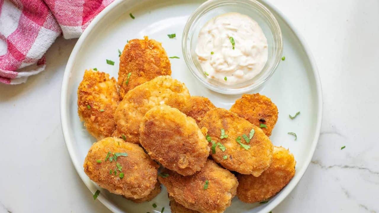 A close up image of cauliflower nuggets on a plate with sauce on the side.