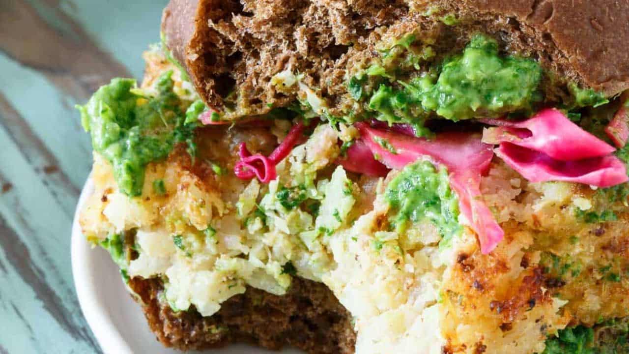 Cheddar cauliflower burger with pickled cabbage and pesto on a plate.