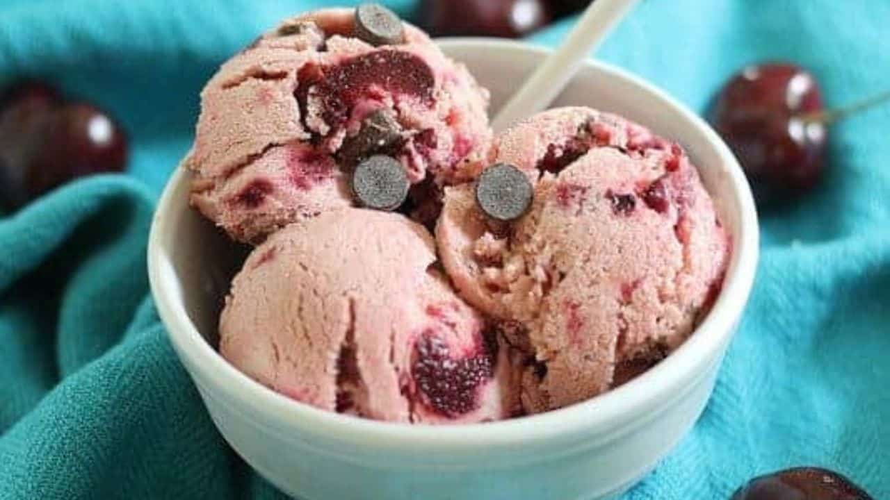 Cherry chocolate chip frozen yogurt in a white bowl on a turquoise kitchen towel.