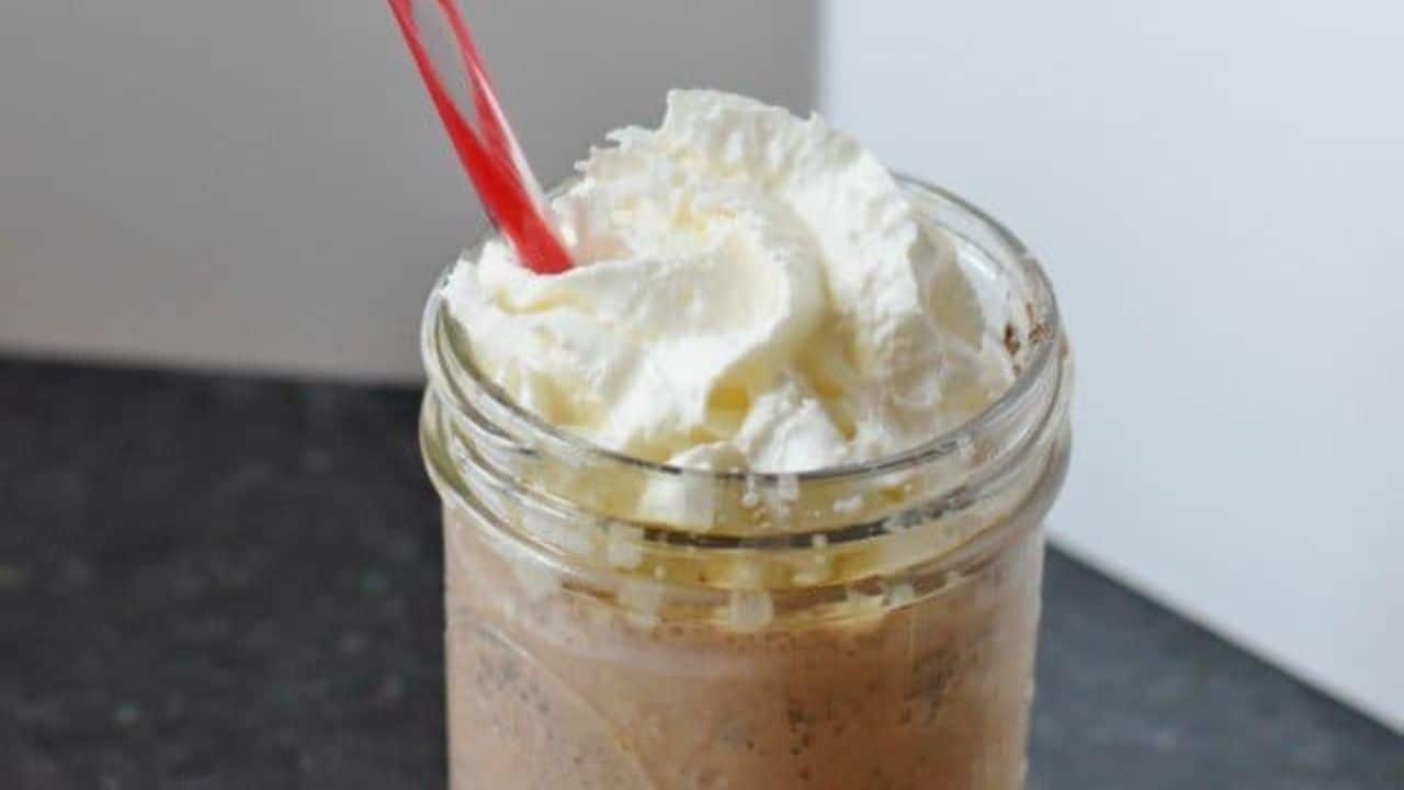 Image shows a closeup of a Copycat Java Chip Frappuccino in a mason jar with whipped cream and a straw.