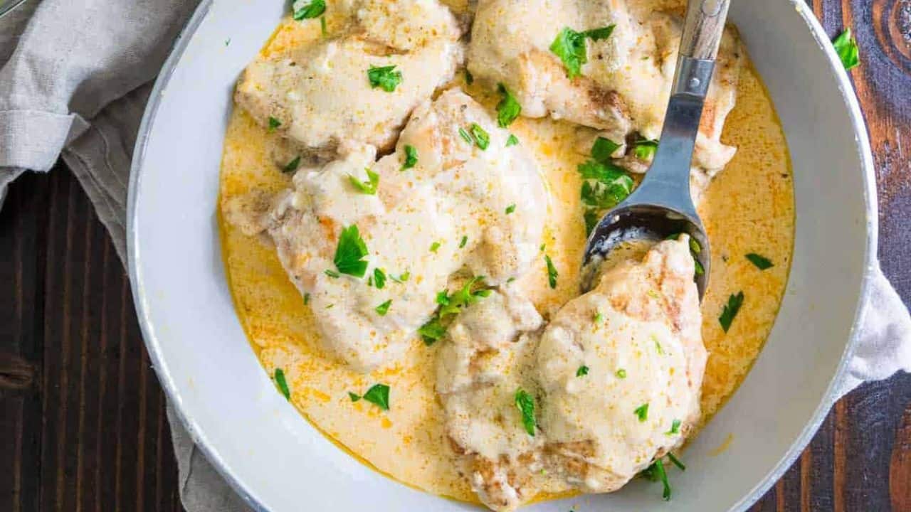 Cream cheese chicken in a white skillet.