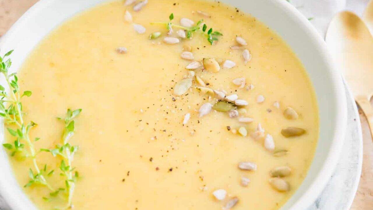 A bowl of creamy root vegetable soup with sprigs of thyme.