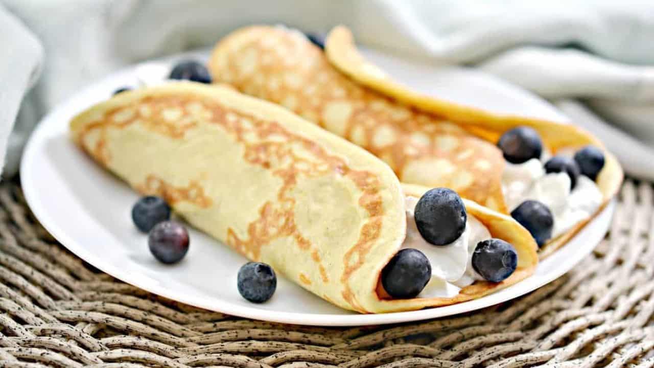 A plate of crepes with blueberries on it.
