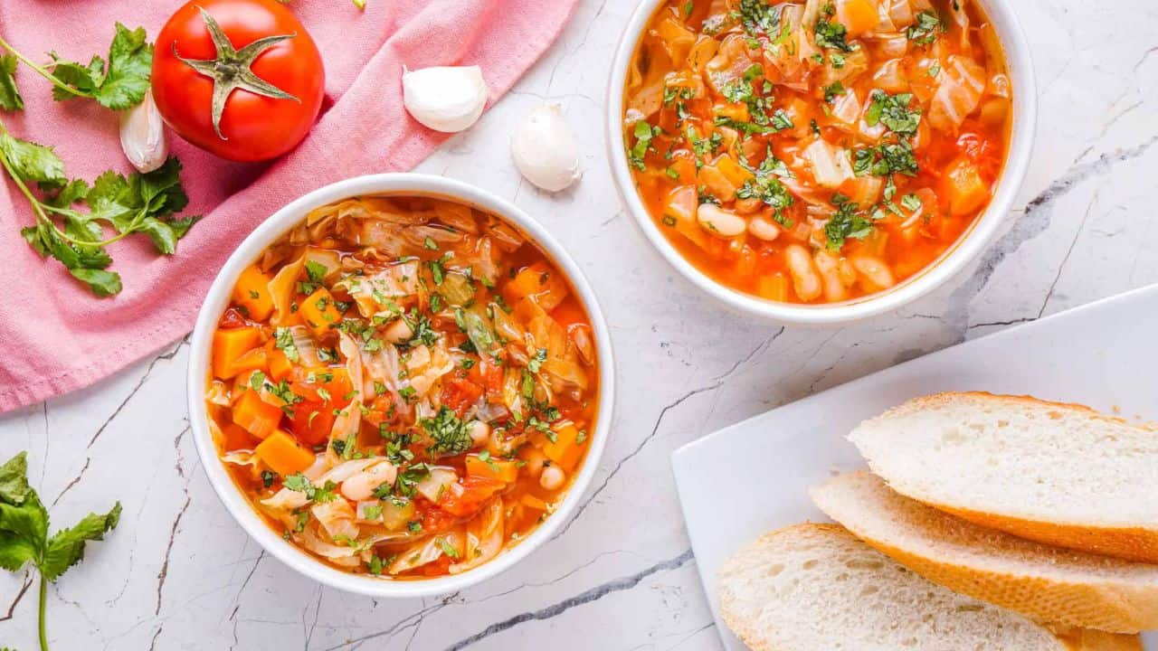 An overhead image of two cabbage soups in a white serving bowl.