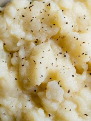 A bowl of mashed potatoes topped with ground black pepper.