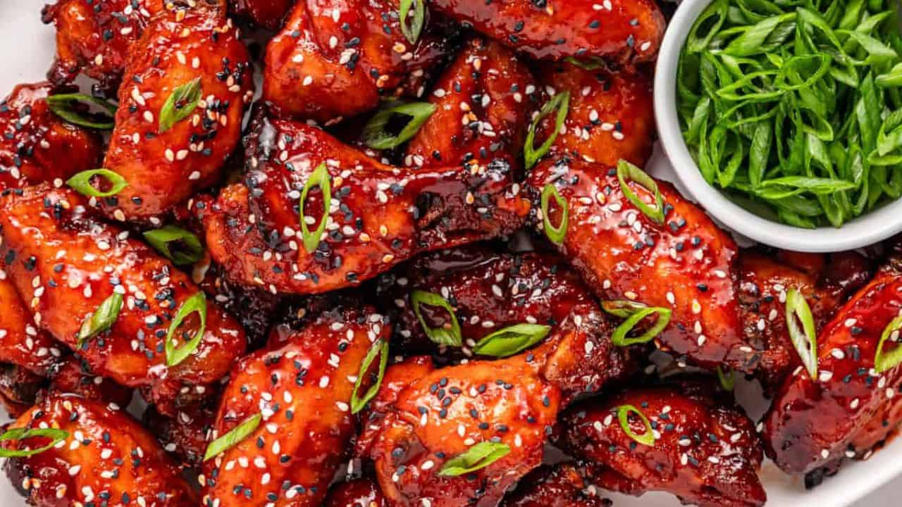 Delicious Korean chicken wings garnished with sesame seeds and green onions on a plate.