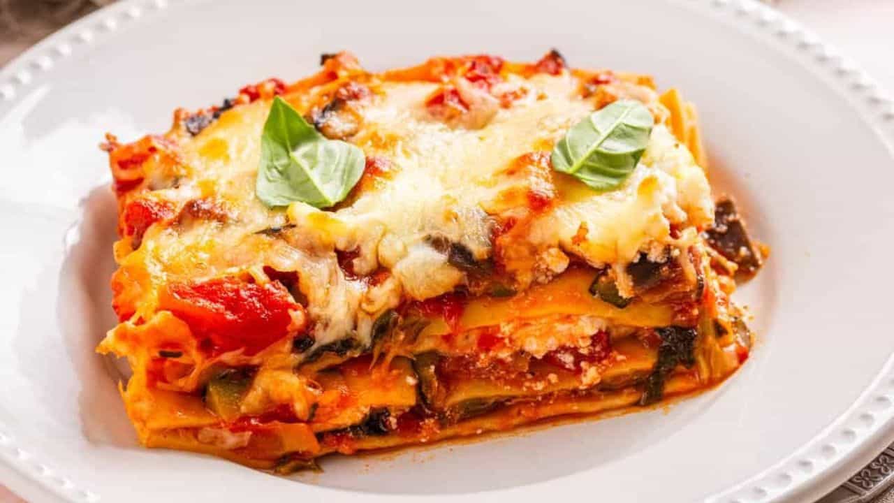 An image of a slice of vegetable lasagna on a white serving plate.