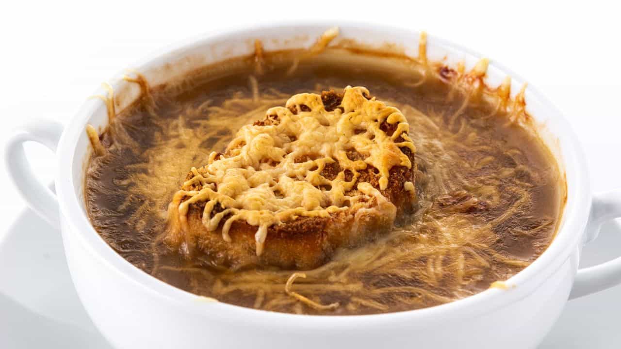 A bowl of French onion soup topped with a slice of toasted bread and melted cheese.