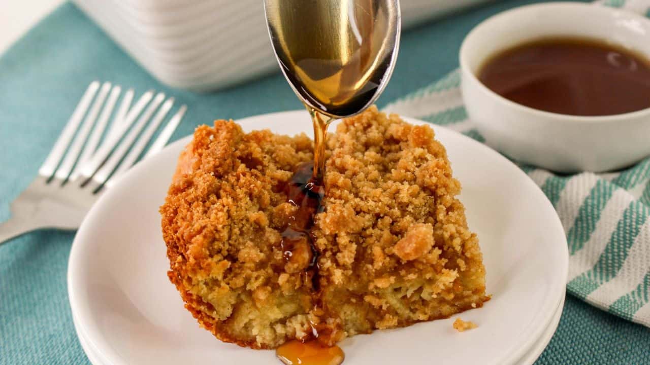 Baked French Toast Casserole with Croissants in a white rectangular dish, with a side of syrup.