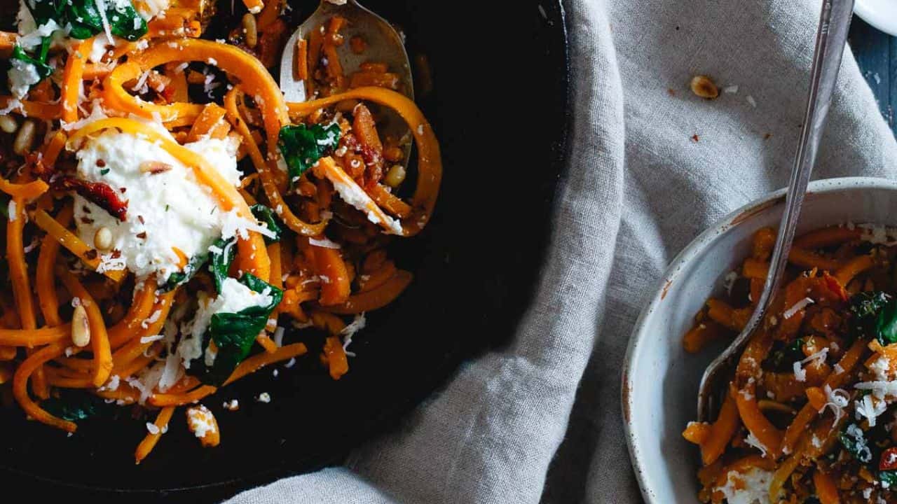 Butternut squash noodles with spinach, ricotta and garlic in a cast iron skillet.