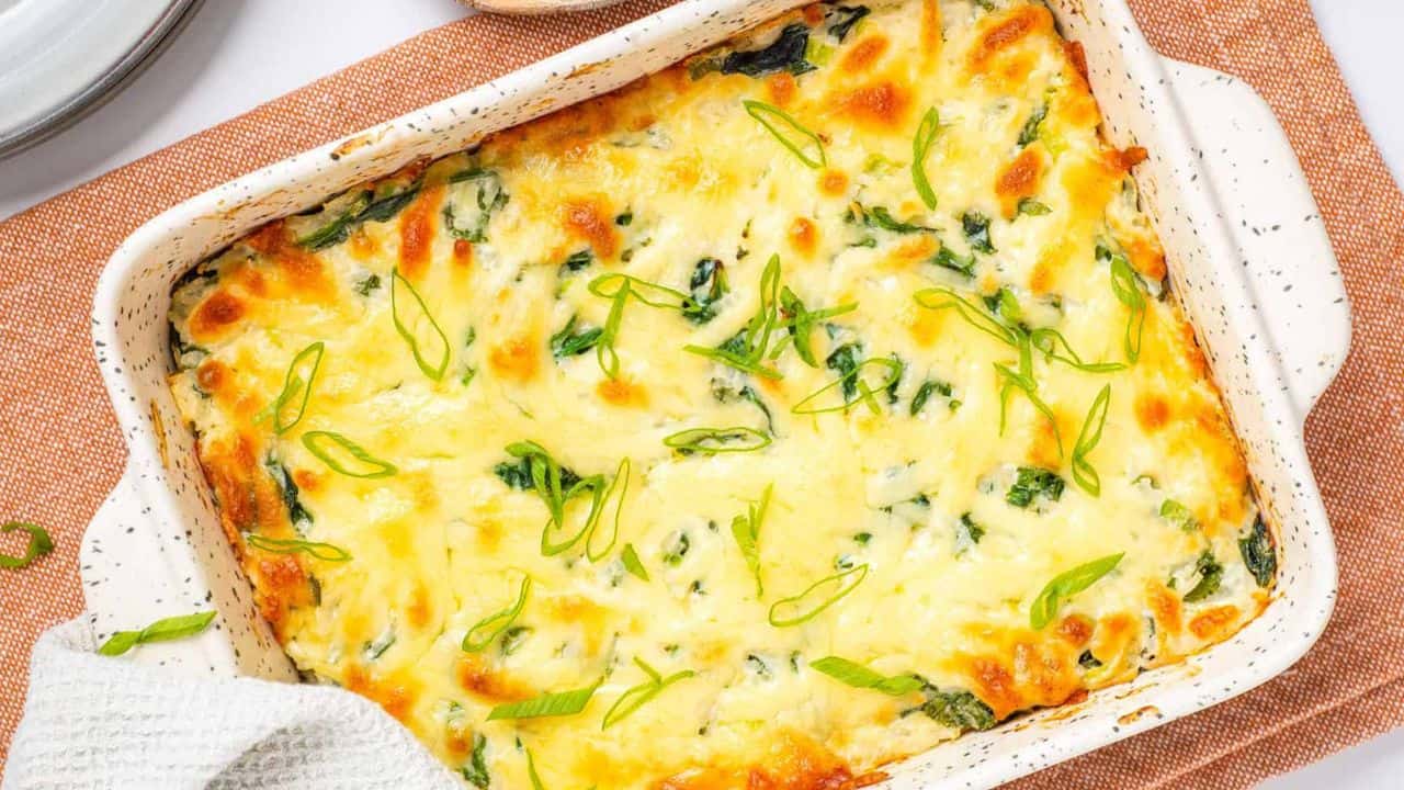 An overhead image of green rice casserole in a white baking dish.