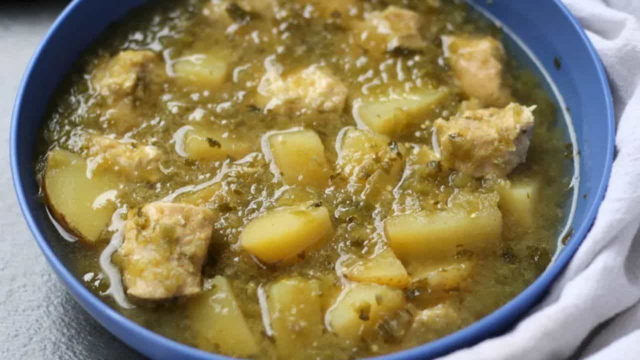 Chicken Verde with Potatoes Soup in a blue bowl with spoon.