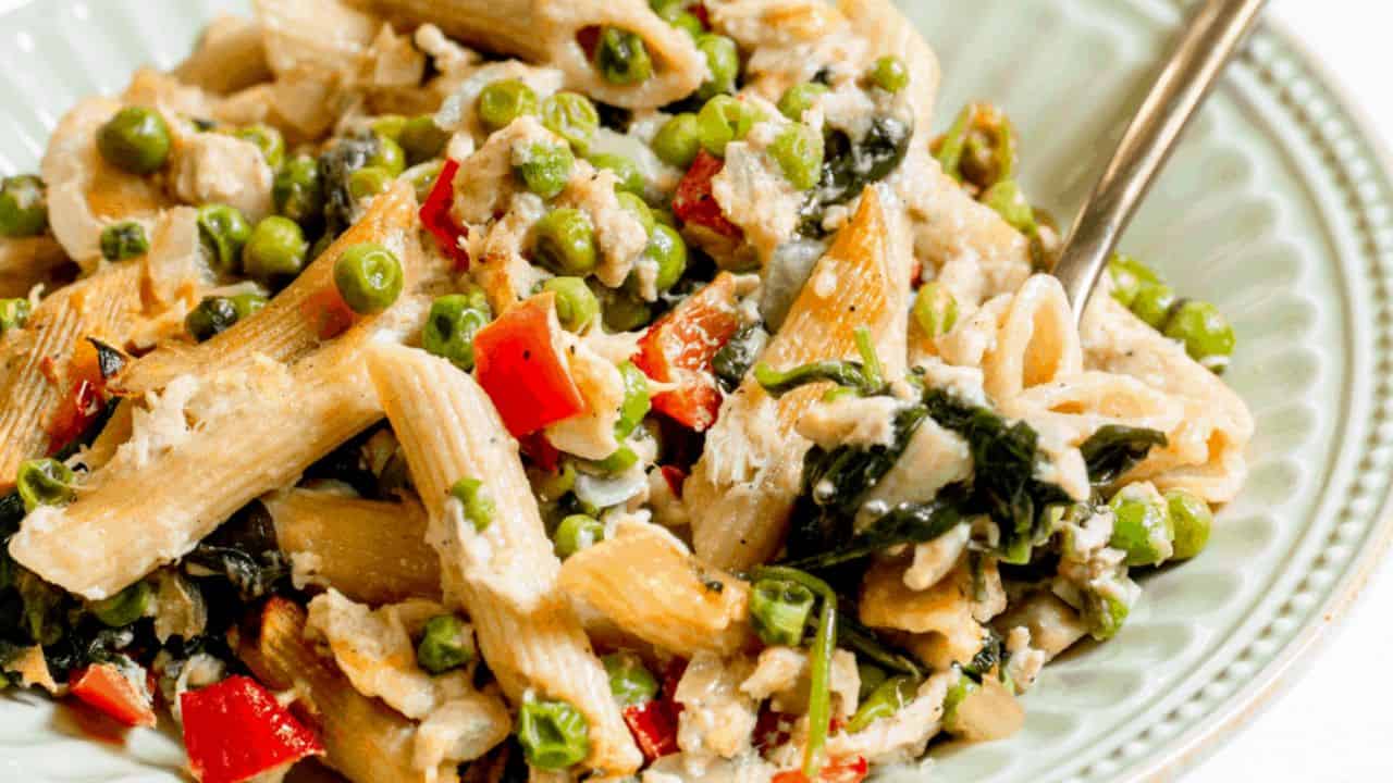 Tuna noodle casserole with vegetables in a shallow light green bowl.