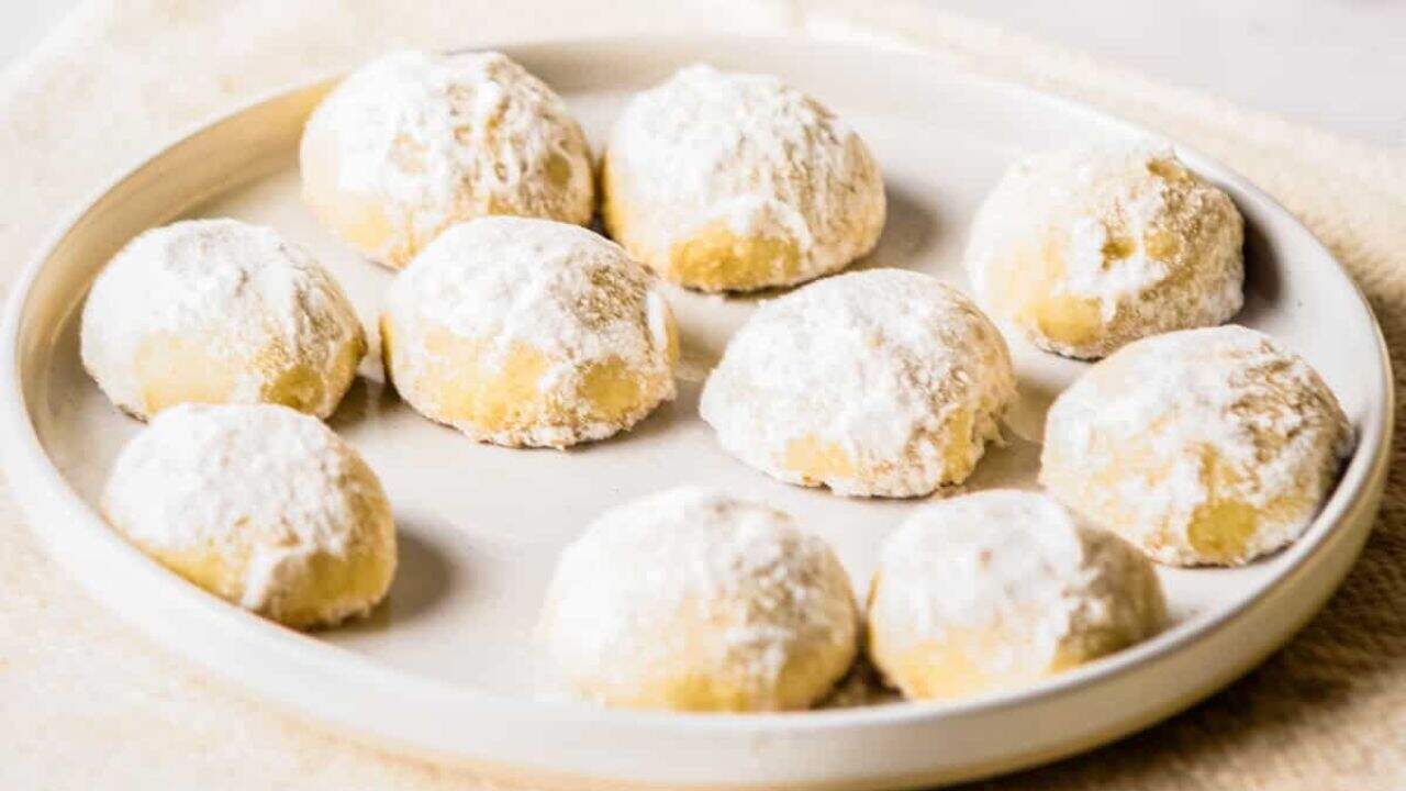 A close-up view of holiday butter cookies on a white plate.