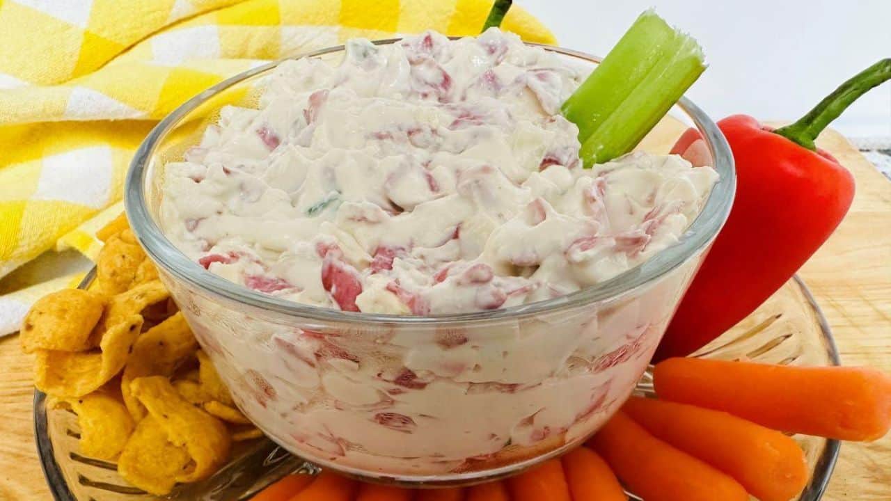 A bowl of dip with carrots and celery.