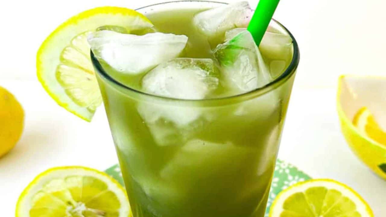A refreshing green drink with ice and a slice of lemon, served in a clear glass.