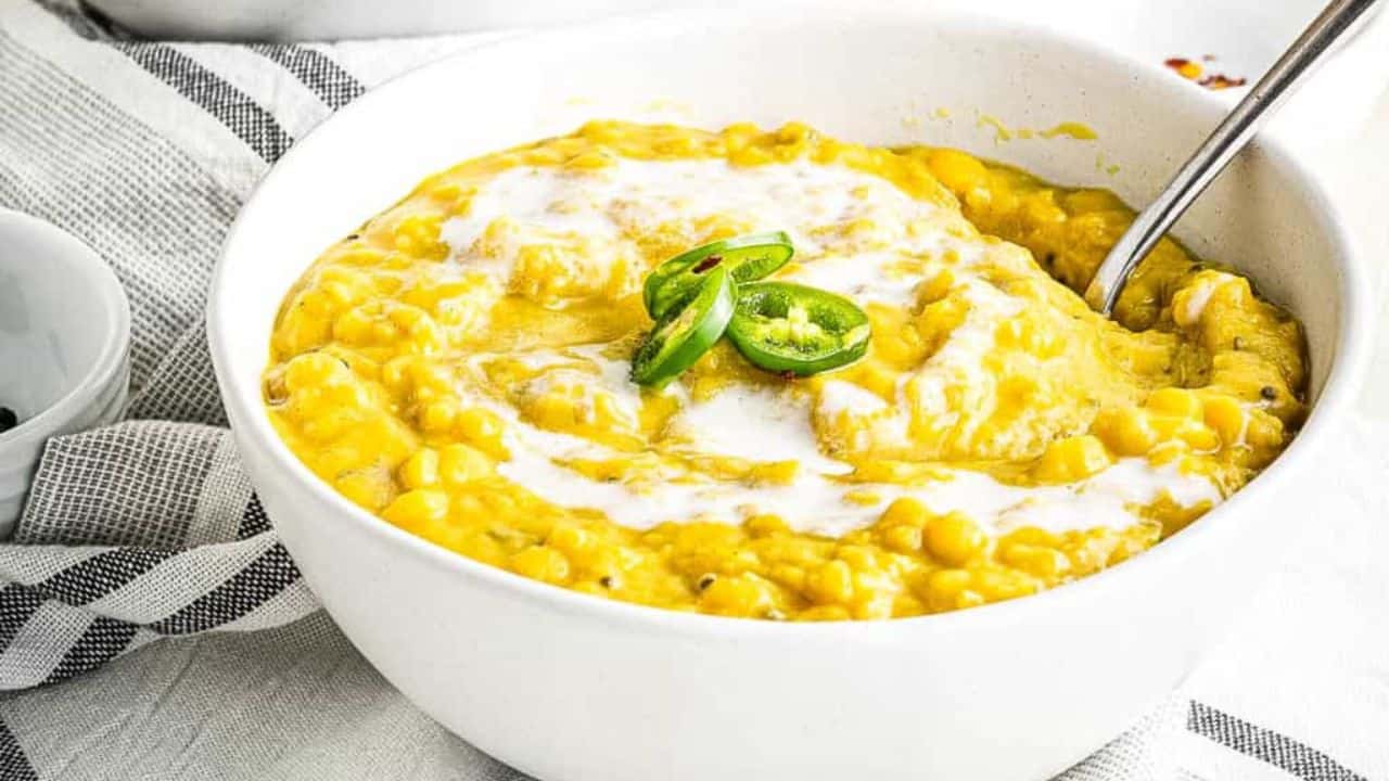 Overhead shot of 2 bowls of dal soup garnished with coconut milk and sliced green chiles.