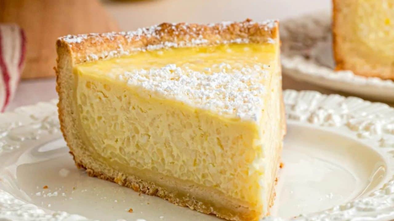 A slice of rice pie with a golden crust and powdered sugar on top, served on a white plate.
