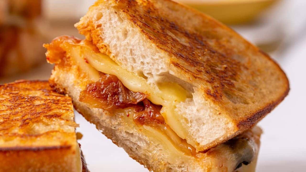 An image of a sliced kimchi grilled cheese sandwich resting on the other slice.
