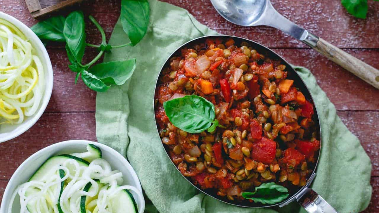 Lentil bolognese garnished with basil in a metal dish.