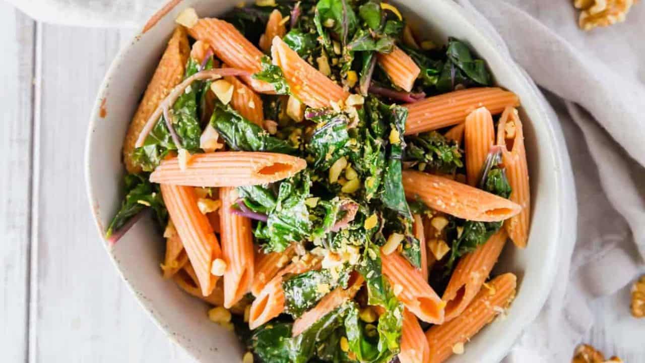 Red lentil pasta with garlic lemon greens in a bowl.