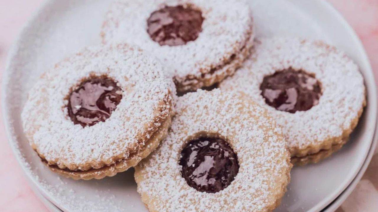 An overhead image of three Linzer cookies on a plate.