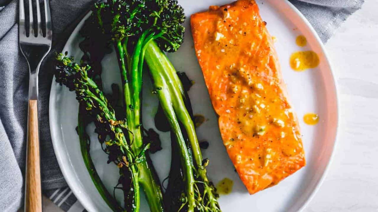 Maple mustard air fryer frozen salmon filet with broccolini on a plate.