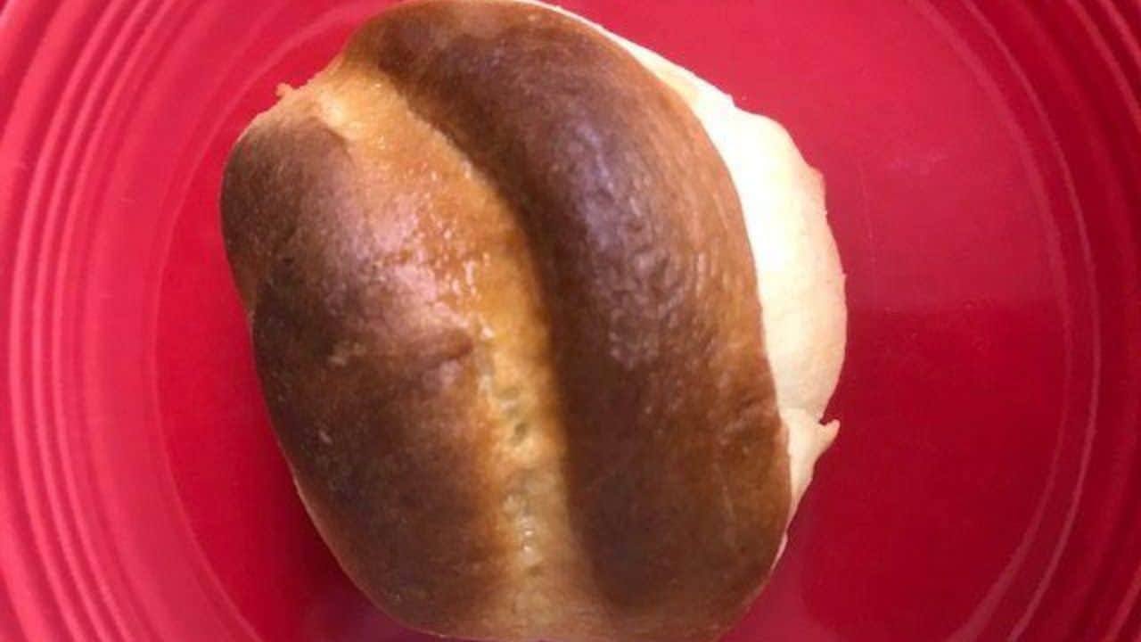 A single bread roll, the star of many cherished bread recipes, rests on a vibrant red plate.