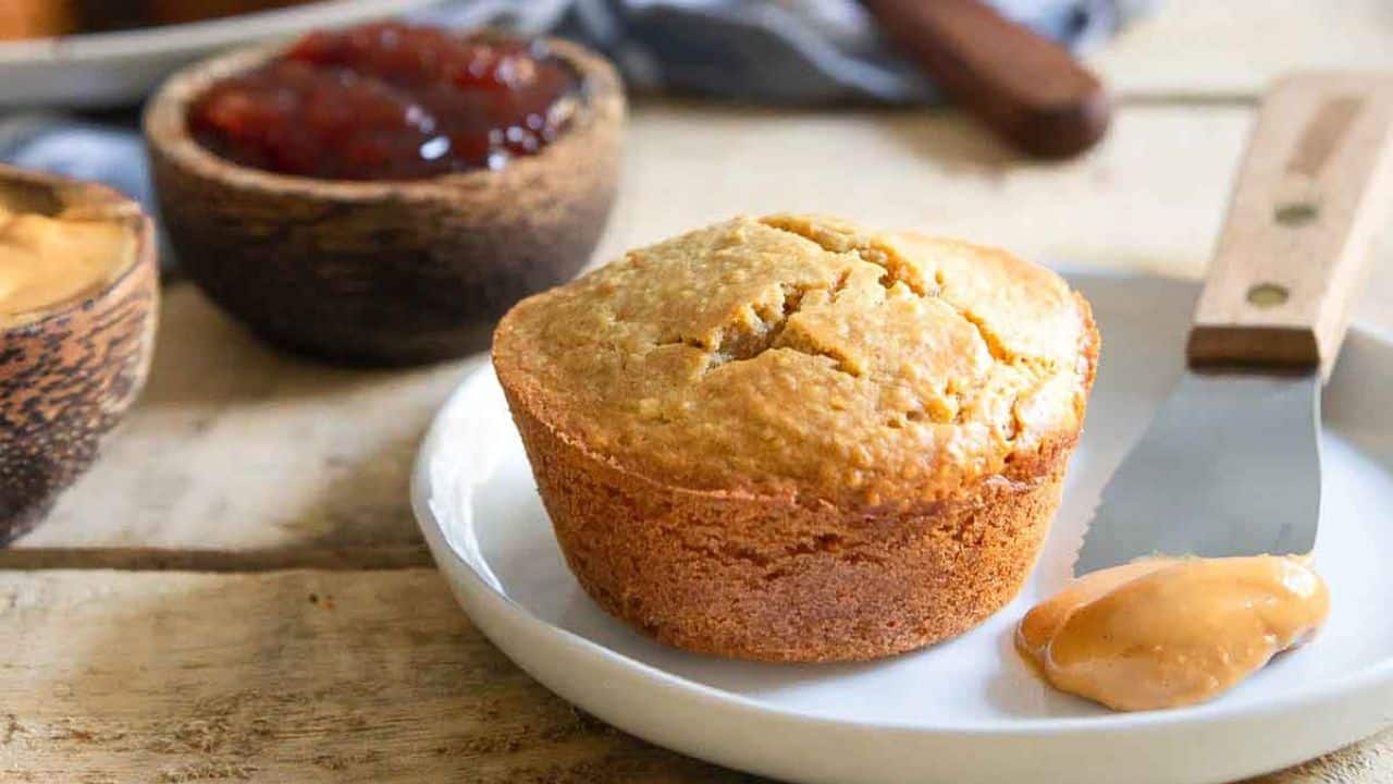 Peanut butter and jelly muffins on a plate with a spatula with peanut butter.