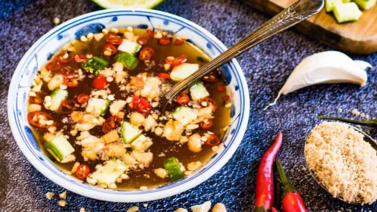 Overhead shot of Prik Nam Pla dipping sauce with limes and peanuts on the side.