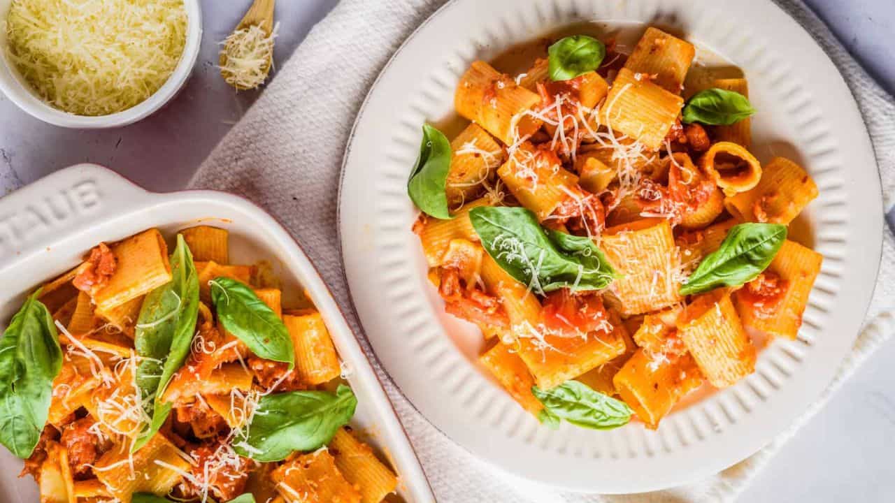 Overhead view of rigatoni arrabbiata dish placed on a white plate and baking dish.