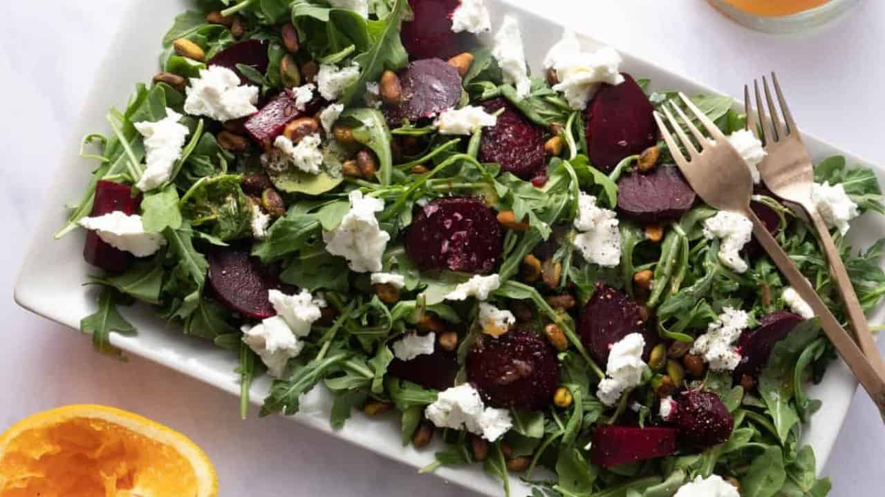Close up of beet salad on a white platter with two forks on the right side.